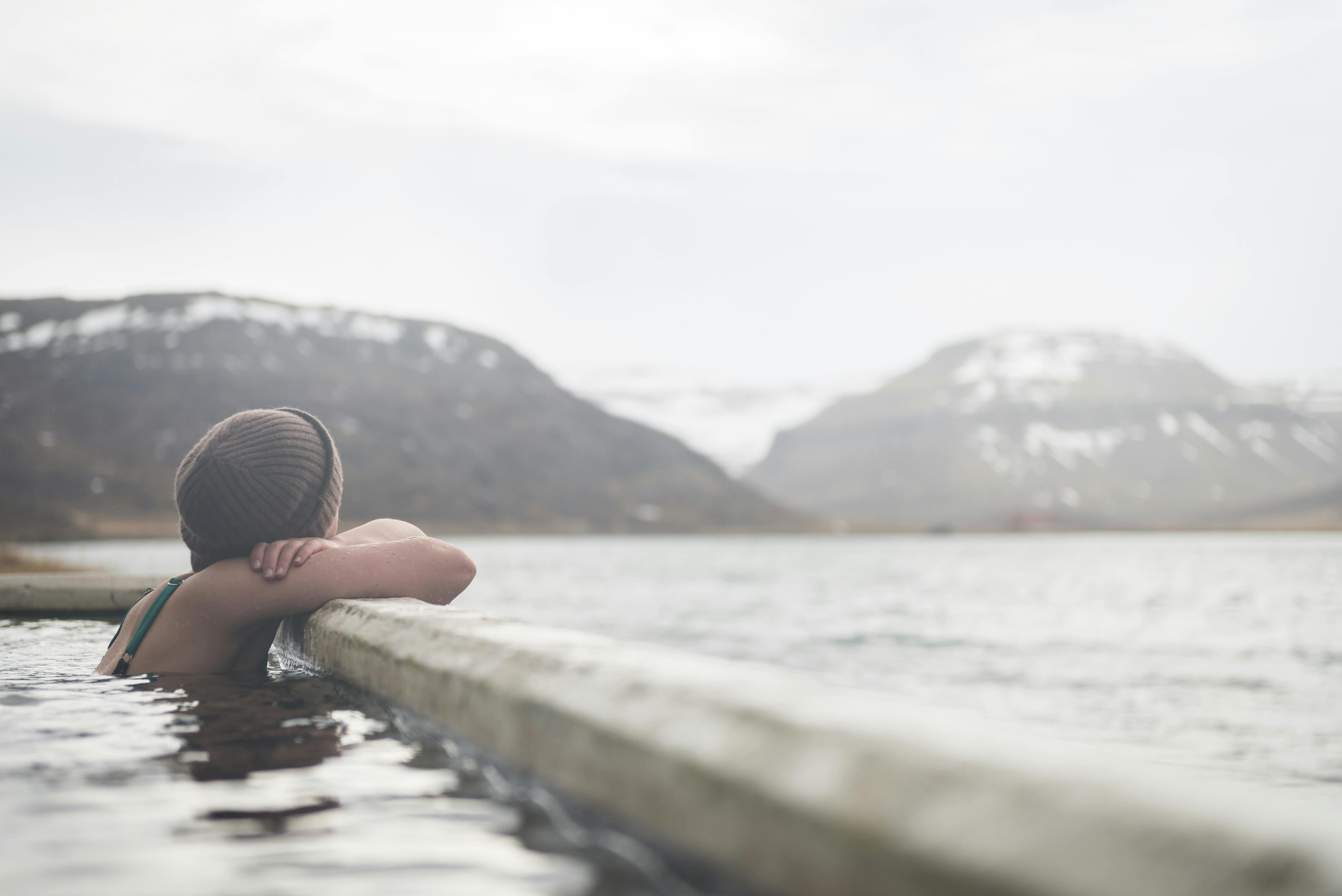 Lady in hot springs pool looking out at a snowy mountain landscape