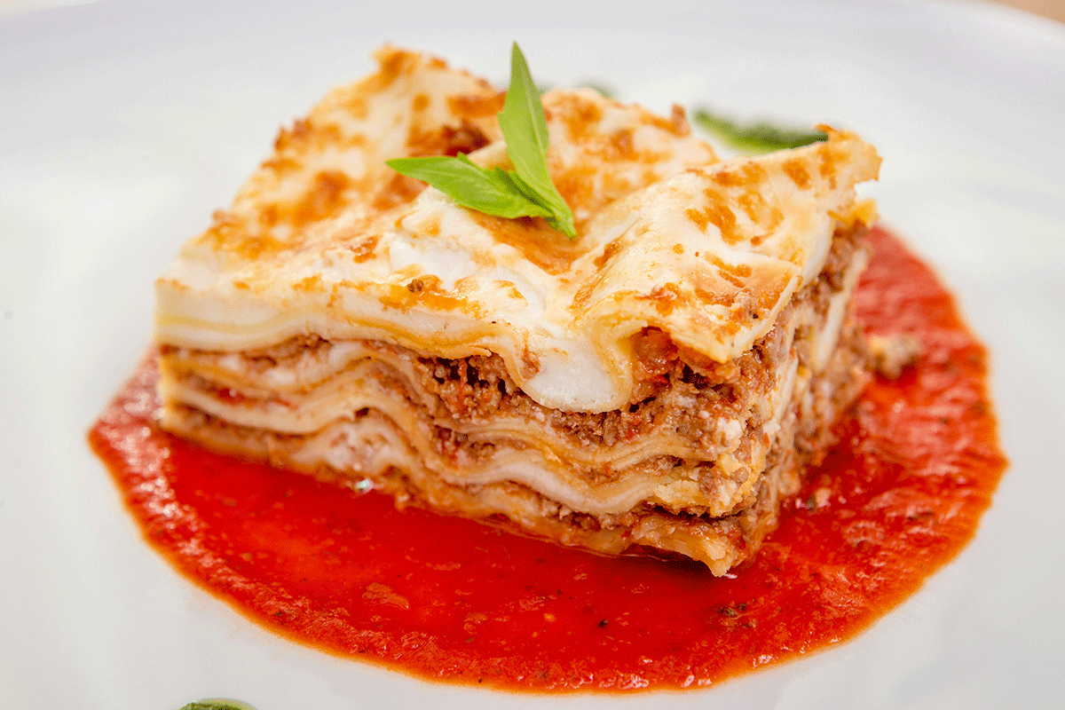 slice of lasagna on plate surrounded by sauce