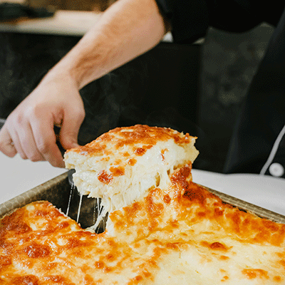 cheesy lasagna being pulled from a pan